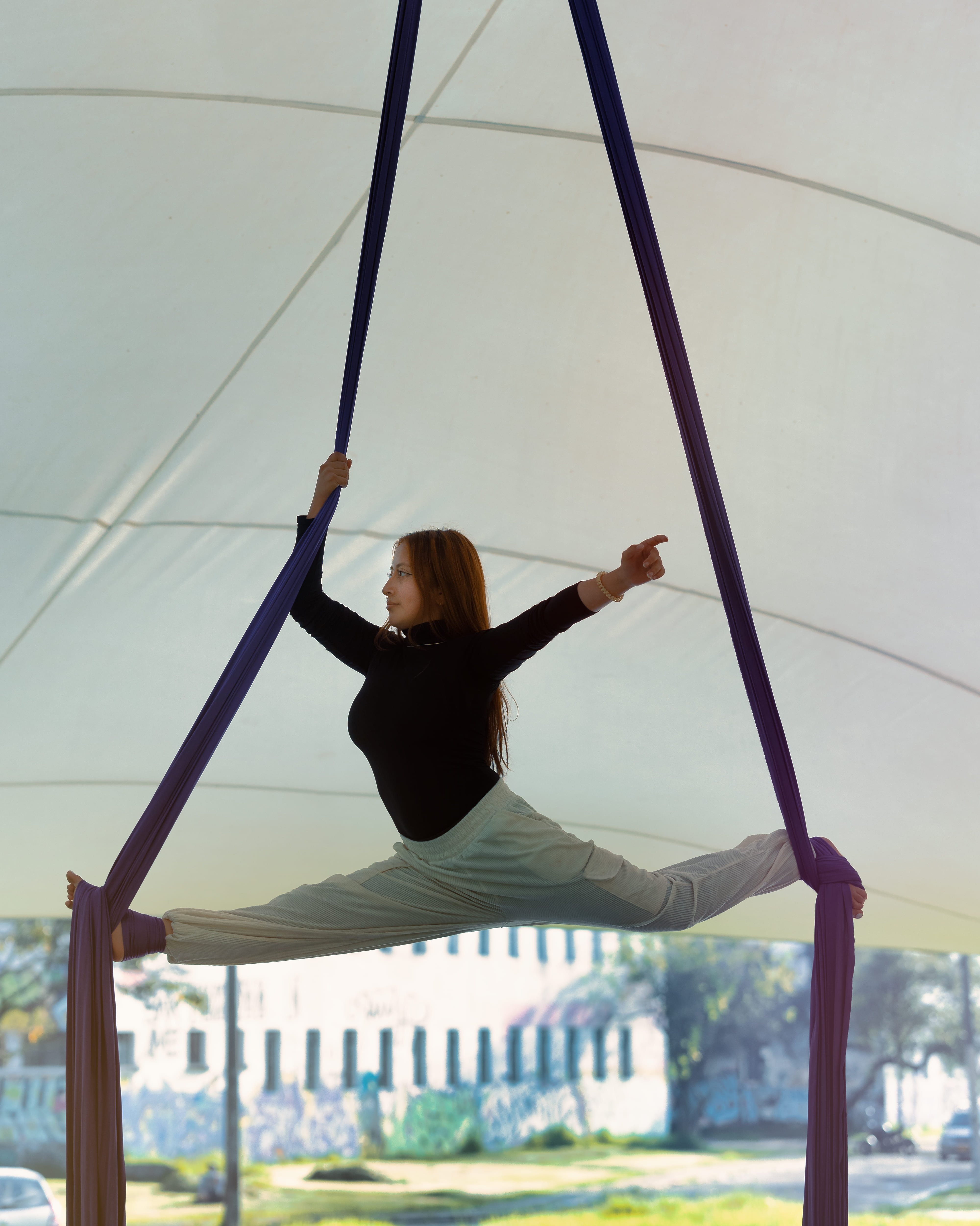Artista de telas aéreas haciendo split bajo carpa al aire libre