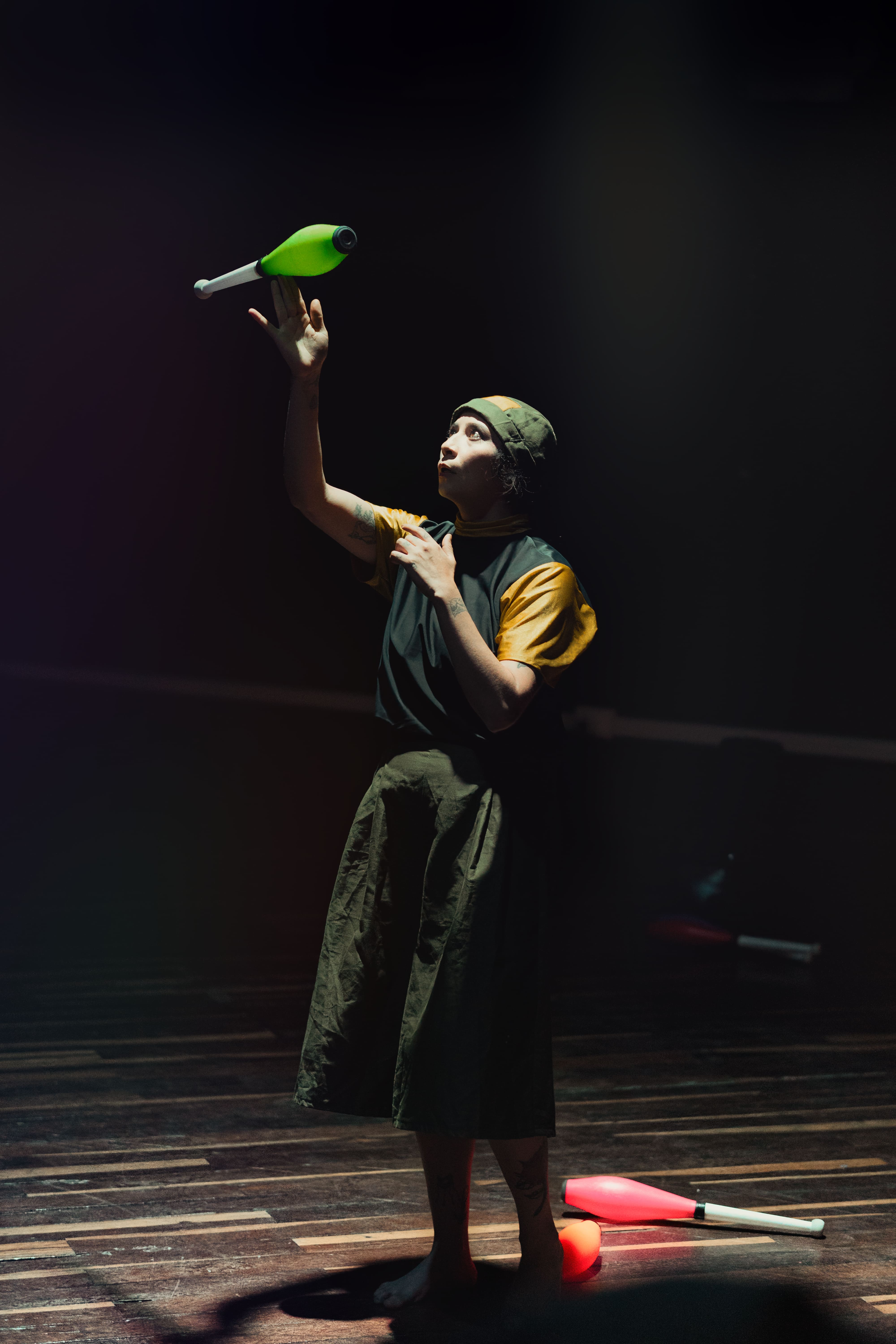 Malabarista lanzando clava en escenario con luz dramática