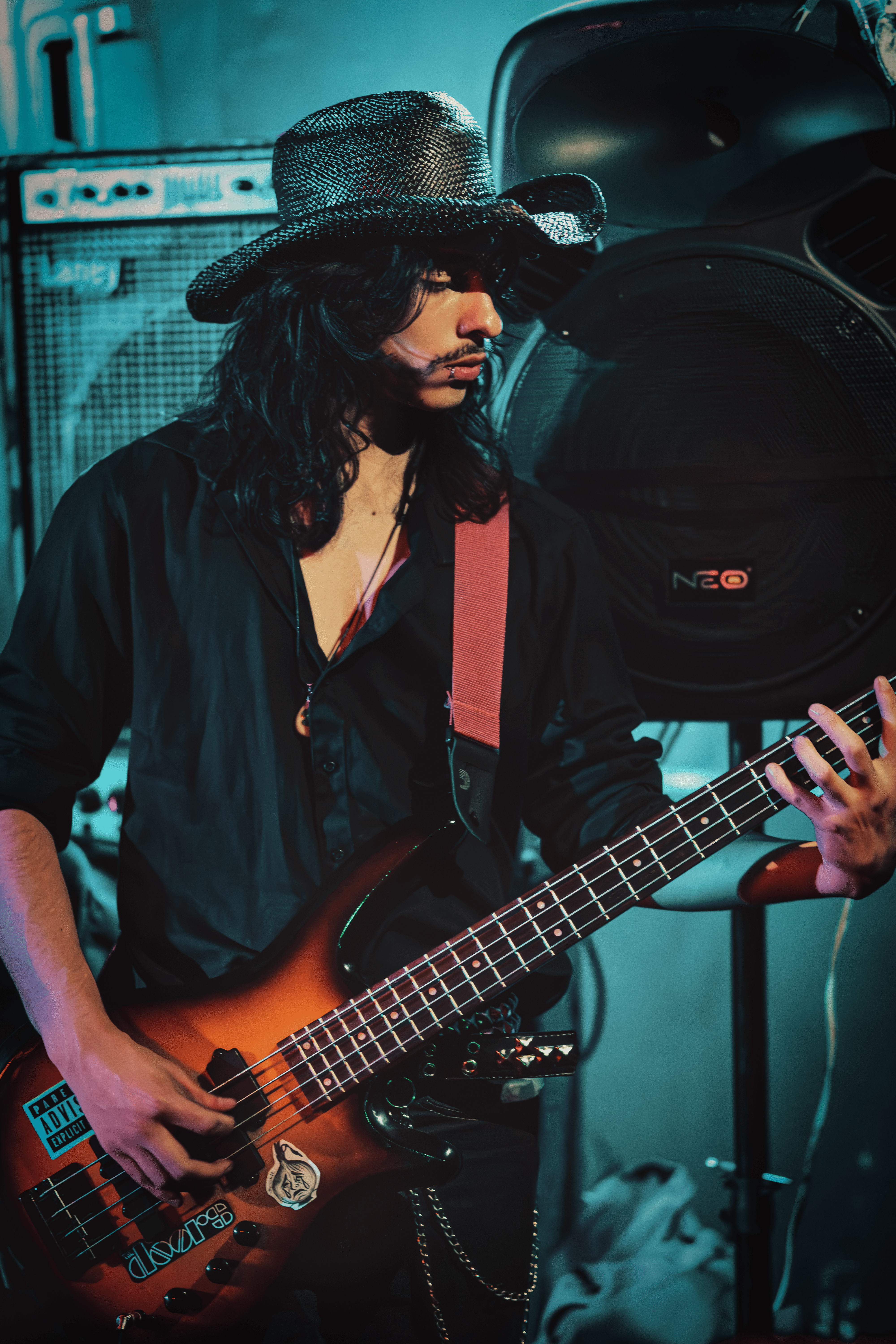 Bajista con sombrero y actitud rockera bajo luces azules