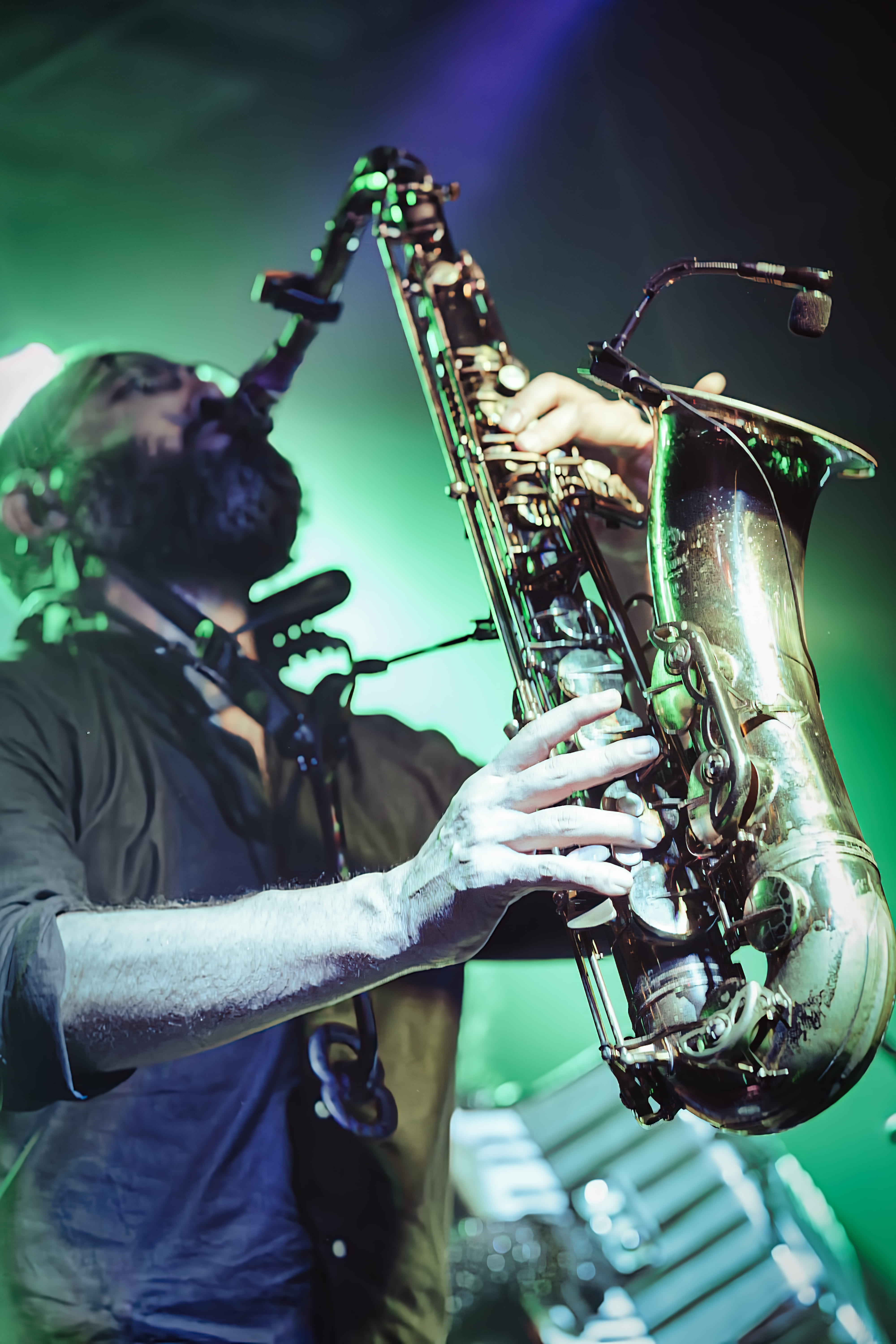 Saxofonista inclinado hacia atrás bajo luces verdes