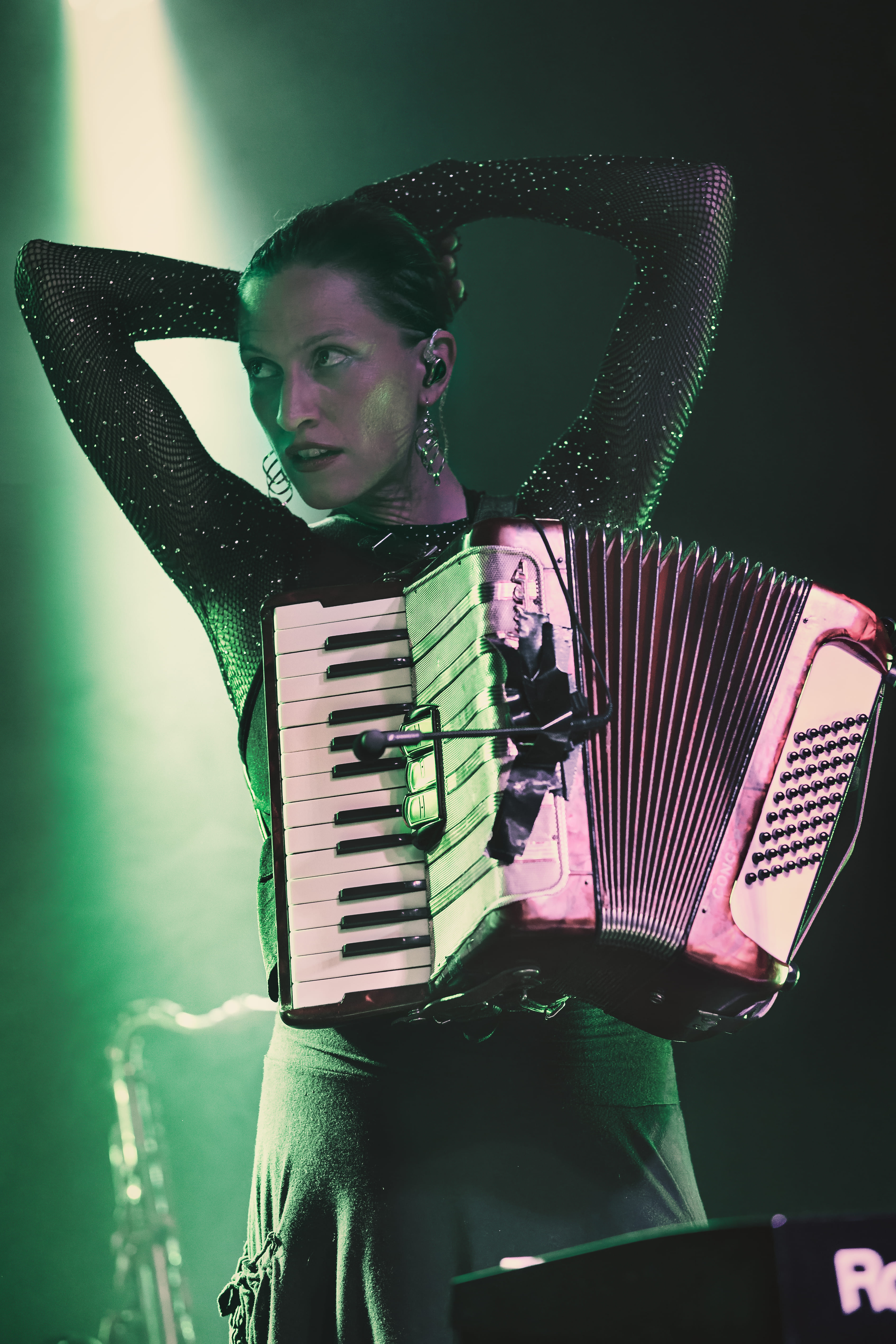 Mujer tocando acordeón con vestido brillante bajo luz verde
