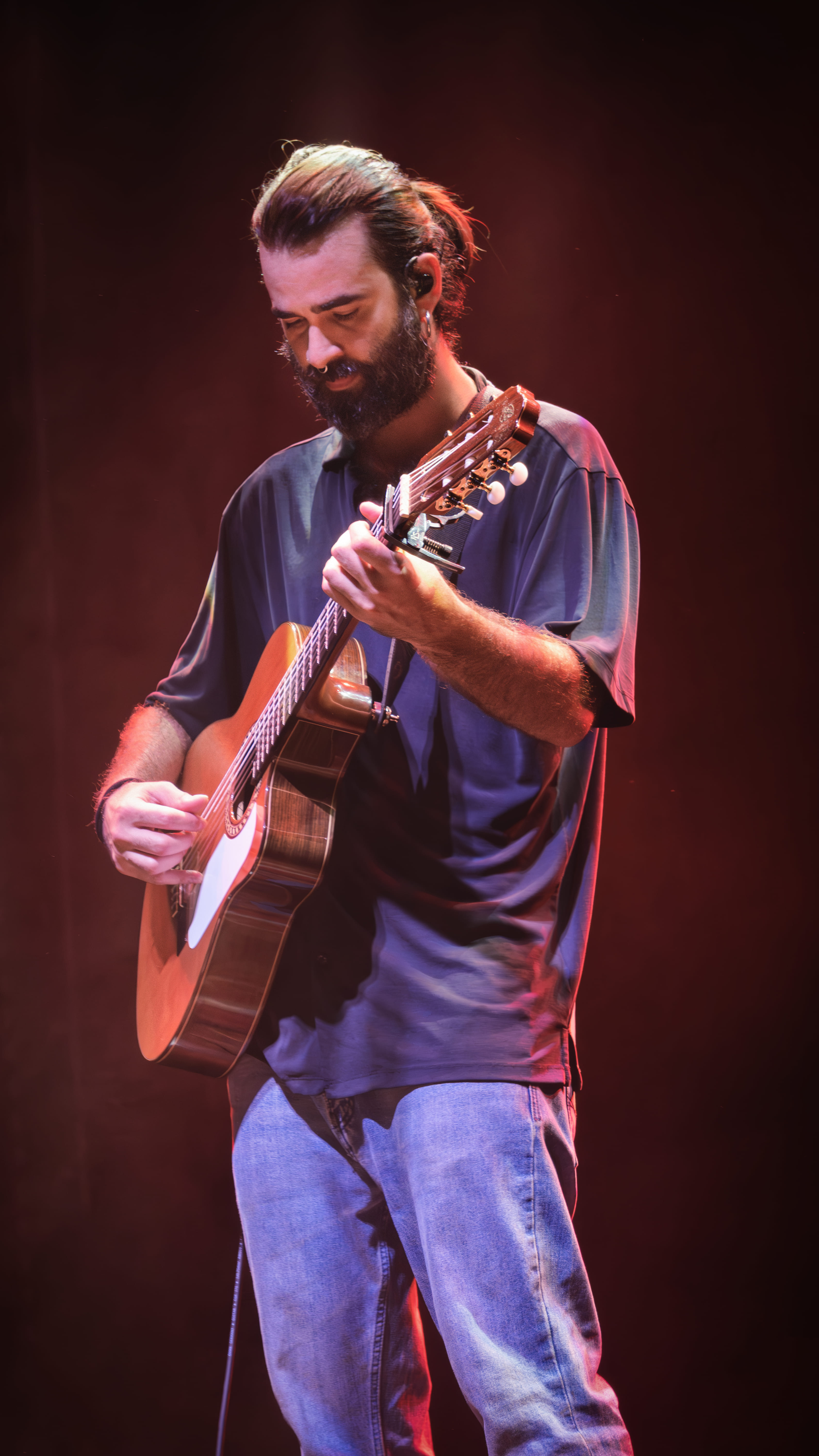 Guitarrista tocando guitarra clásica con luz rojiza