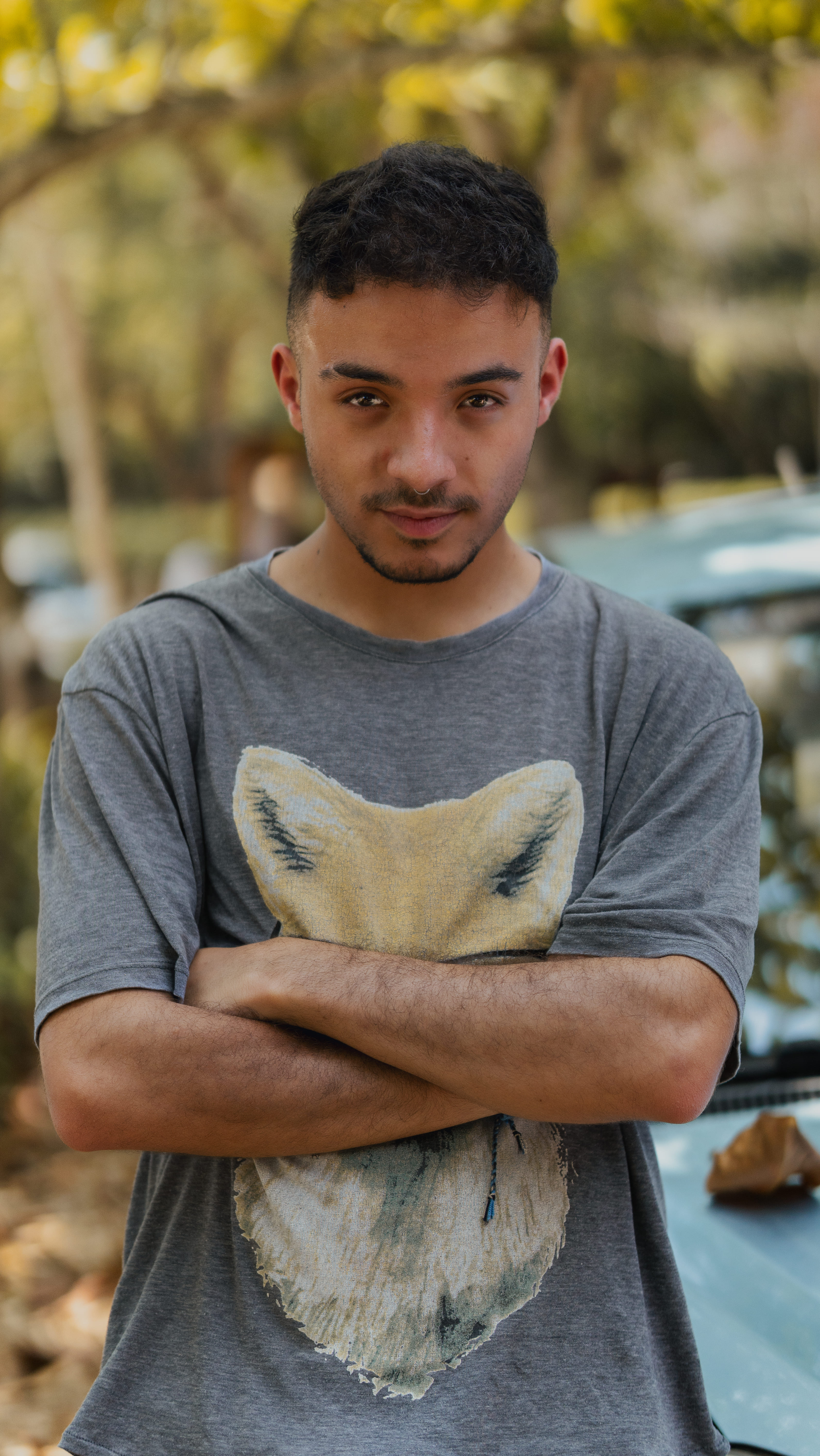Chico joven con brazos cruzados y camiseta de zorro al aire libre