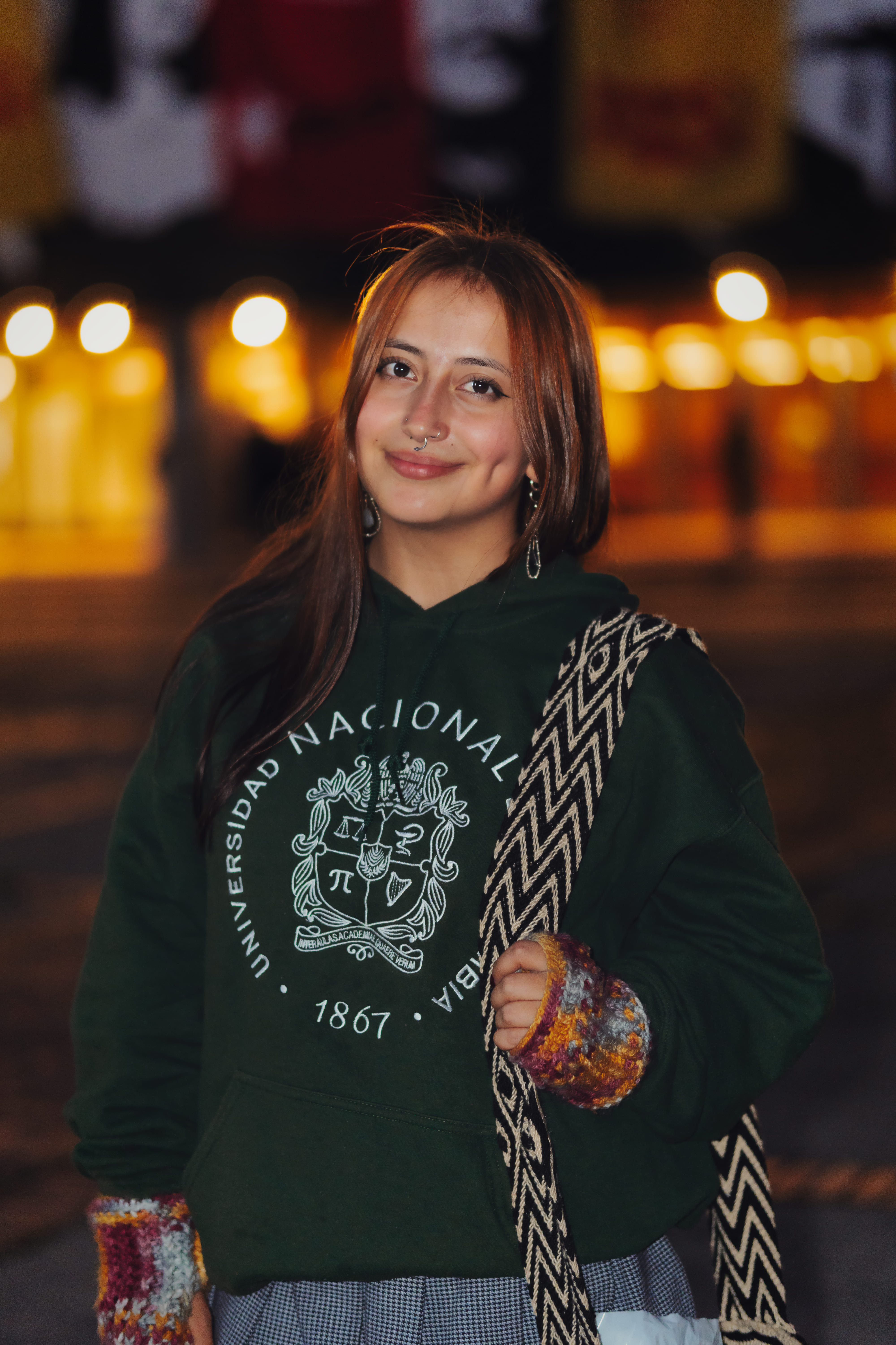 Chica con buzo de Universidad Nacional con bokeh de luces nocturnas