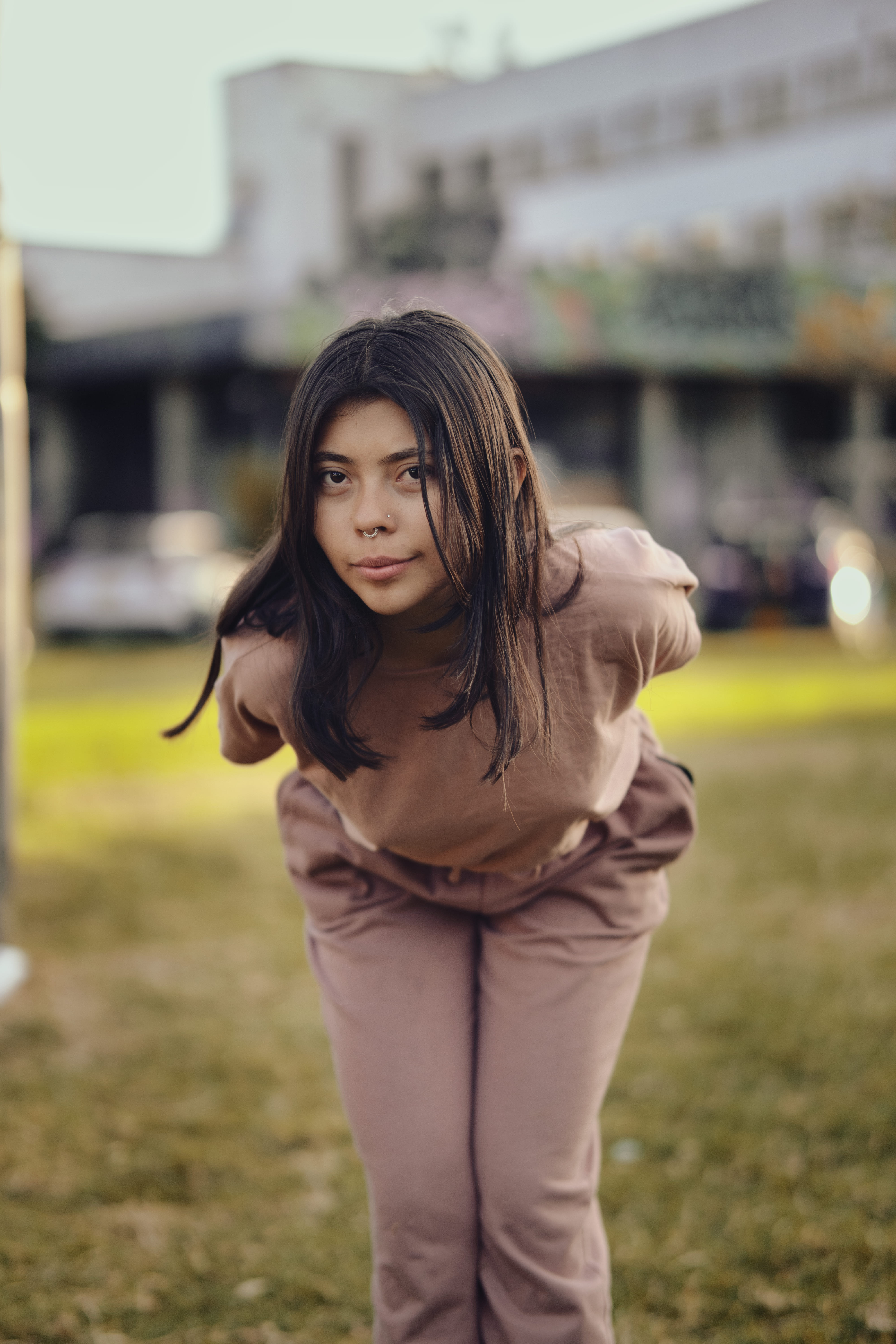 Chica inclinada hacia adelante en parque con luz natural